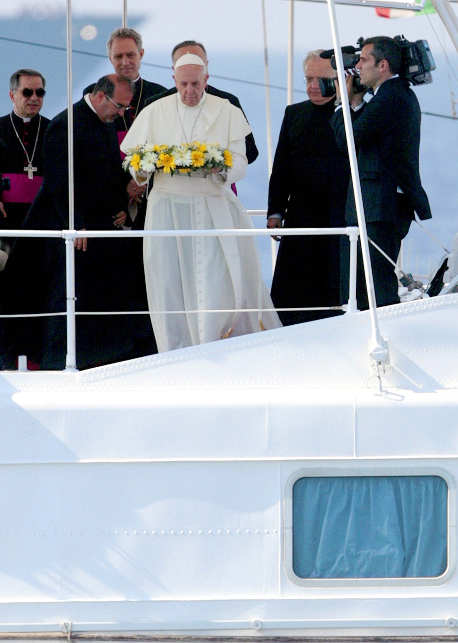 Pope Francis tosses a wreath of flowers into the Mediterranean Sea off the Italian island of Lampedusa in this July 8, 2013, file photo. The pope threw a wreath to honor the memory of immigrants who have died trying to cross from Africa to reach a new life in Europe. Marking the first anniversary of his Lampedusa visit, the pope said the the tragic deaths of thousands searching for a better future should trigger compassion and action, not indifference. (Credit: CNS photo/pool.)