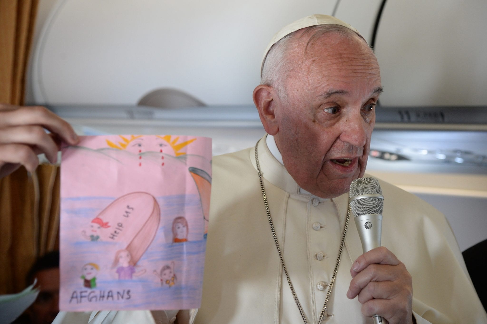 In this April 16, 2016 file photo, Pope Francis shows drawings made by children on his flight back to Rome following a visit to the Greek island of Lesbos. (Credit: Filippo Monteforte/Pool Photo via AP.)