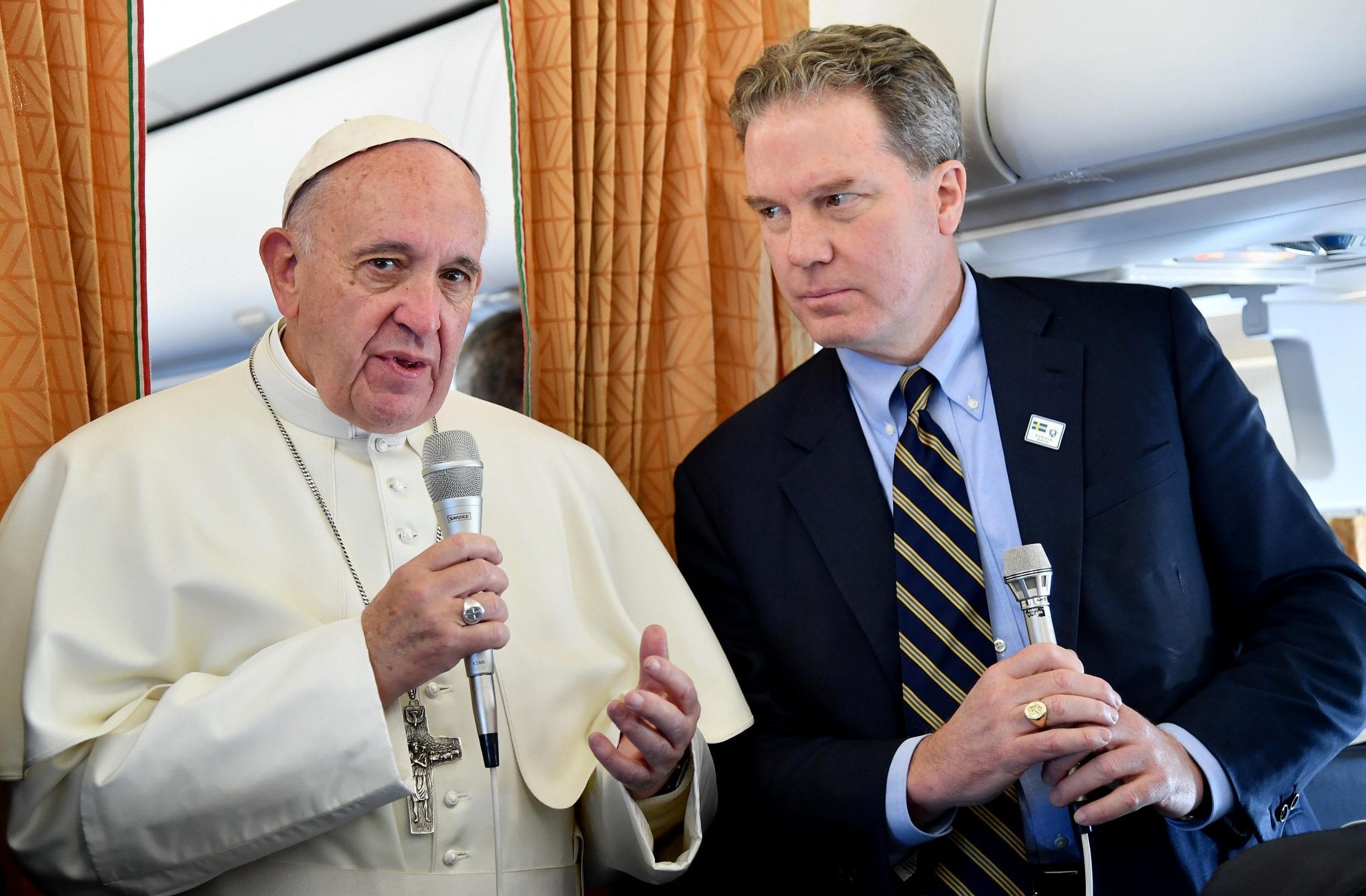 Pope Francis is flanked by Vatican Spokesman Greg Burke as he speaks with journalists on his way to Malmo, Sweden, Monday, Oct. 31, 2016. Pope Francis traveled to secular Sweden on Monday to mark the 500th anniversary of the Protestant Reformation, a remarkably bold gesture given his very own Jesuit religious order was founded to defend the faith against Martin Luther's "heretical" reforms five centuries ago. (Credit: Ettore Ferrari/Pool Photo via AP.)