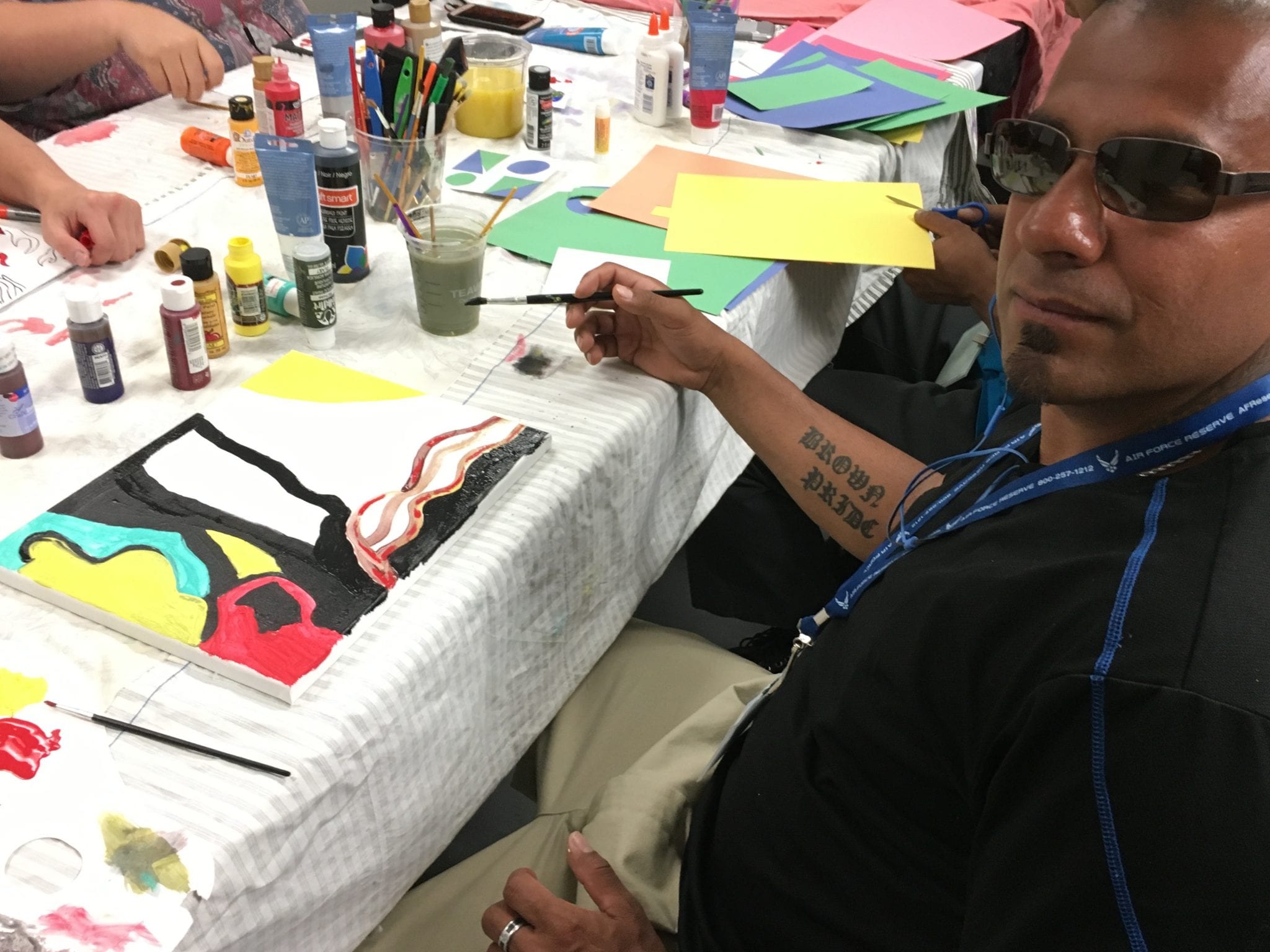 Pedro, a guest at Denver Rescue Mission, explains that his painting symbolizes life being covered in shadow (problems) with water representing life. Then you come into the light by overcoming the problems. This work and others like it will become part of an exhibition at Denver Rescue Mission. (Credit: Shannon Levitt.)