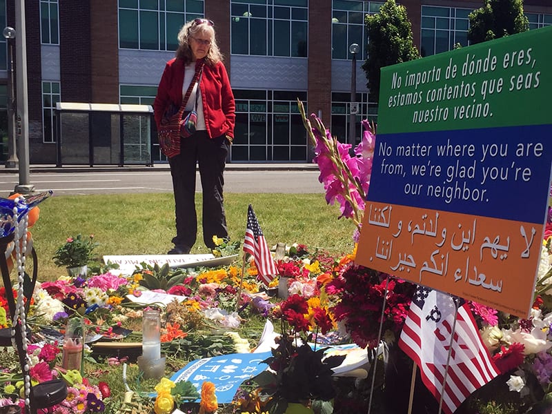 Betsy Toll of Portland pays her respects on May 31, 2017, at a makeshift memorial that has sprung up outside the Hollywood Transit Station in Portland, Oregon, where three men were stabbed on a train. (Credit: RNS photo by Emily McFarlan Miller.)