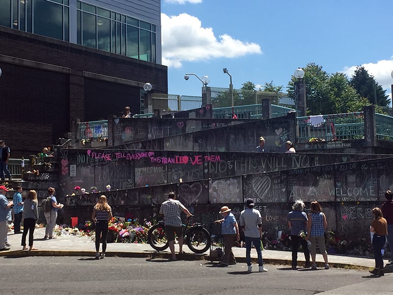 People pause to take photos or leave messages, flowers or other items on May 31, 2017, at a makeshift memorial that has sprung up outside the Hollywood Transit Station in Portland, Oregon, where three men were stabbed on a train. (Credit: RNS photo by Emily McFarlan Miller.)