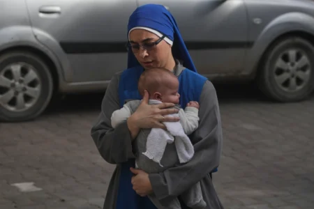 A nun holds a baby as she walks to attend Christmas Eve Mass at the Holy Family Catholic Church in Gaza City, Sunday, Dec. 21, 2025. (Credit: Jehad Alshrafi/AP.)