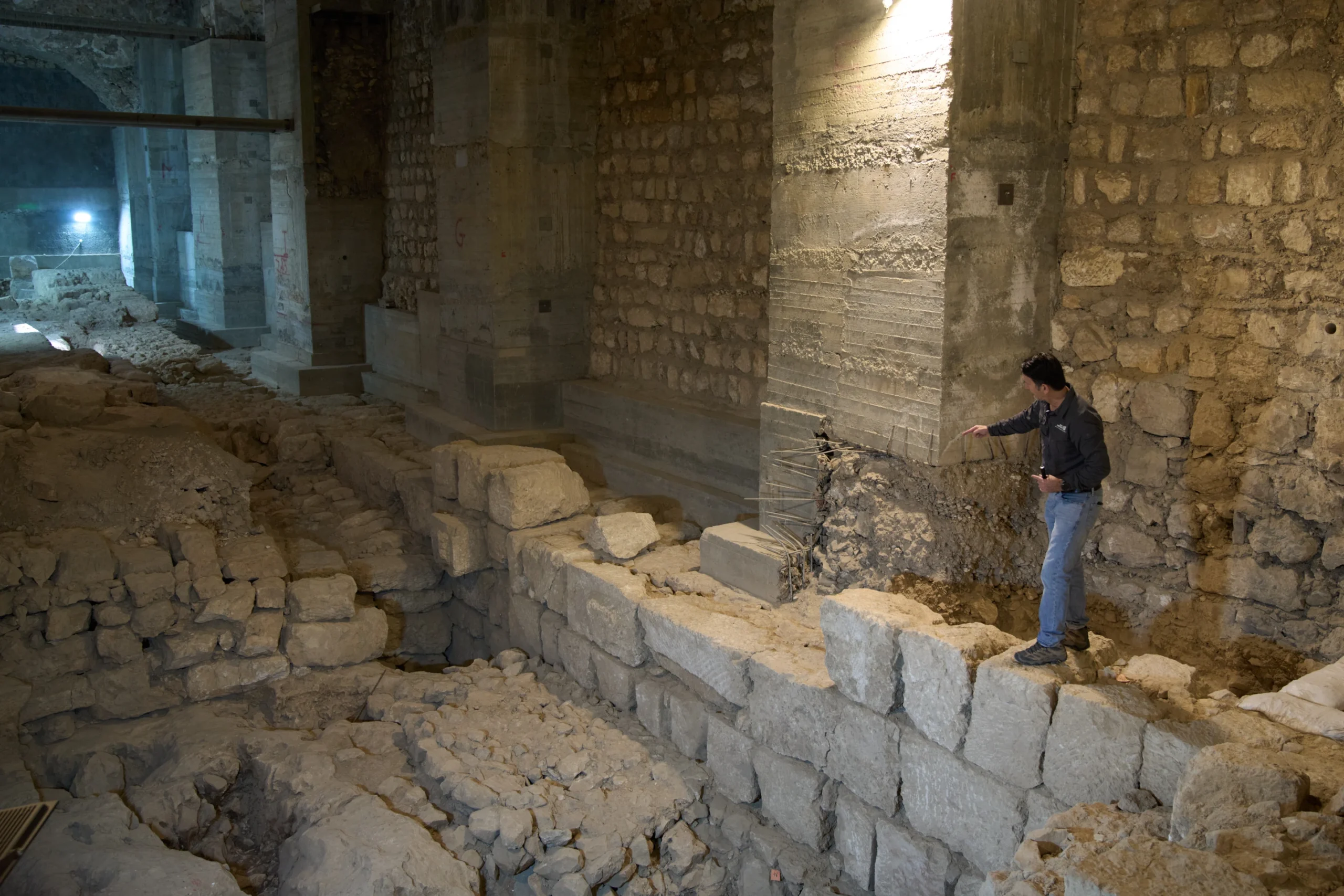 The Jerusalem Regional Archaeologist for the Israel Antiquities Authority, Dr. Amit Re'im, shows a section of an excavation site where, according to the institution, a city wall from the Hasmonean period, dating to the late 2nd century BCE, was uncovered under the Tower of David Citadel Museum, in the Old City of Jerusalem, Monday, Dec. 8, 2025. (Credit: Leo Correa/AP.)
