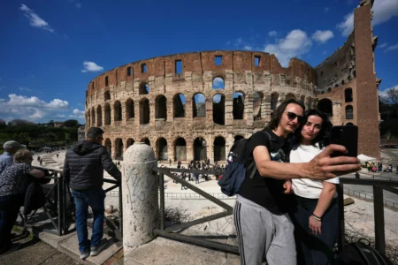 A couple take a selfie photo in front of the new outdoor space created with travertine marble around the Colosseum, during it’s inauguration in Rome, Tuesday, March 17, 2026. (Credit: Andrew Medichini/AP.)