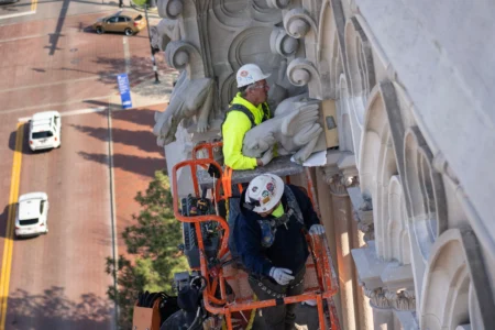 The final new terra cotta gargoyle is installed by Cole Burklund, top, and Blake Priest using a cherry picker high on the Cathedral Basilica of the Assumption, known as "America's Notre Dame," in Covington, Ky., on Monday, March 30, 2026. (Credit: Carolyn Kaster/AP.)