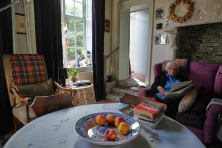 Resident Brigitte Beernaert reads a newspaper inside a house of the Beguinage Ten Wijngaerde in Bruges, Belgium, Wednesday, April 15, 2026. (Credit: Virginia Mayo/AP.)