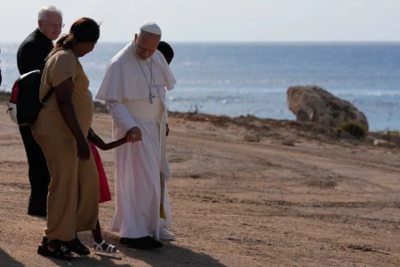 Pope Leo XIV walks together with a migrant family at the Gateway of Europe monument in Lampedusa, Sicily, southern Italy, Saturday, July 4, 2026, during a one-day pastoral visit to the island long associated with the plight of migrants crossing the Mediterranean. (Credit: Alessandra Tarantino/AP.)