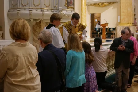 The faithful at the Church of Saint Agnes receive communion on the tongue and while kneeling at the altar rails, in the traditional custom, during one of the Catholic parish’s Latin Masses in St. Paul, Minn., Sunday, June 28, 2026. (Credit: Giovanna Dell’Orto/AP.)
