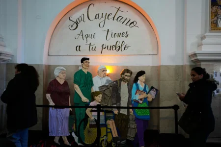 An art installation with a message that reads in Spanish: "Here are your people" and that includes a depiction of Pope Leo XIV is on display inside the Church of San Cayetano during the annual pilgrimage honoring Saint Cajetan, the patron saint of work, in Buenos Aires, Argentina, Friday, Aug. 7, 2026. (Credit: Natacha Pisarenko/AP.)