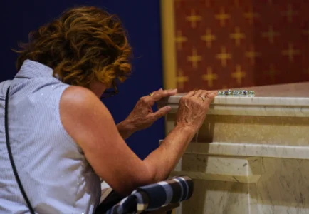 Patricia Stephen of Edmonton, Alberta, Canada, prays at the tomb of Archbishop Fulton Sheen at the Cathedral of St. Mary of the Immaculate Conception in Peoria, Ill., on July 15, 2026. (Credit: Jessie Wardarski/AP.)